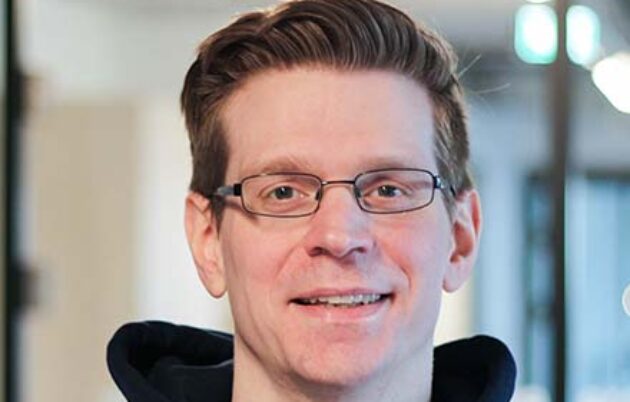 young man with glasses smiling into the camera