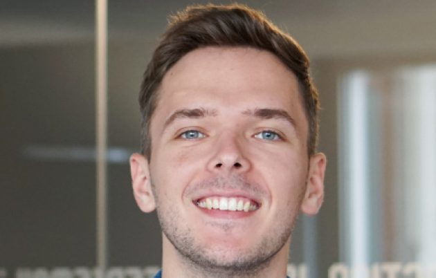 young man with brunette hair smiling into camera