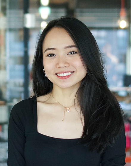 young woman with long dark hair and fair skin smiling into camera