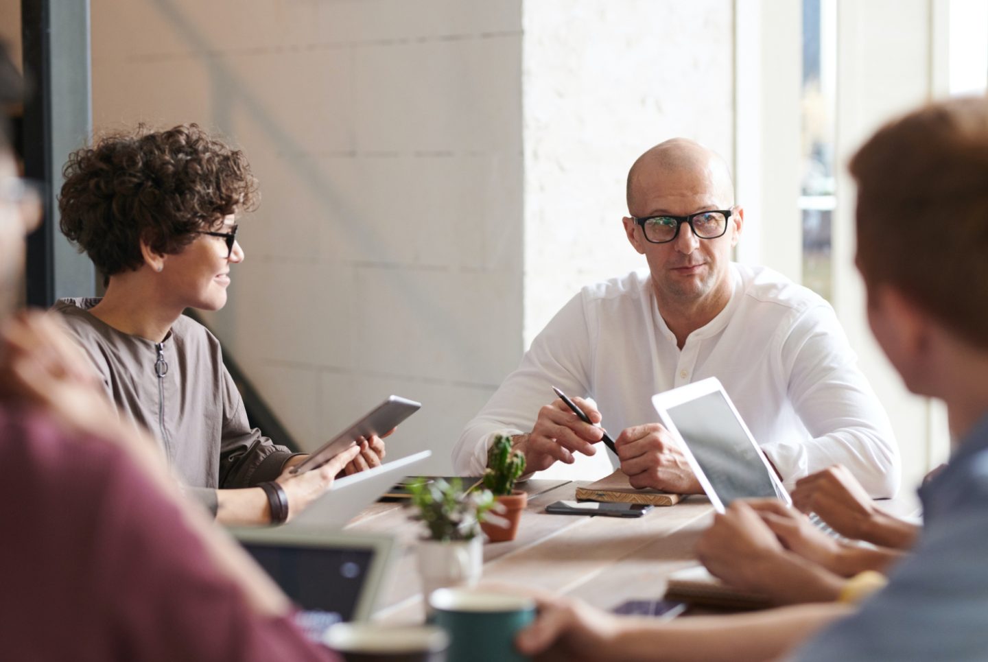 group of adults sitting down at a table and looking at device screens