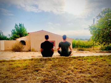 two men in nature with their backs to the camera meditating