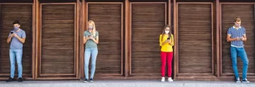 four people standing far apart looking down at their phones