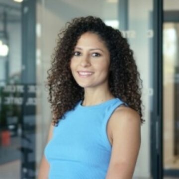 image of young woman with curly brunette hair smiling into the camera