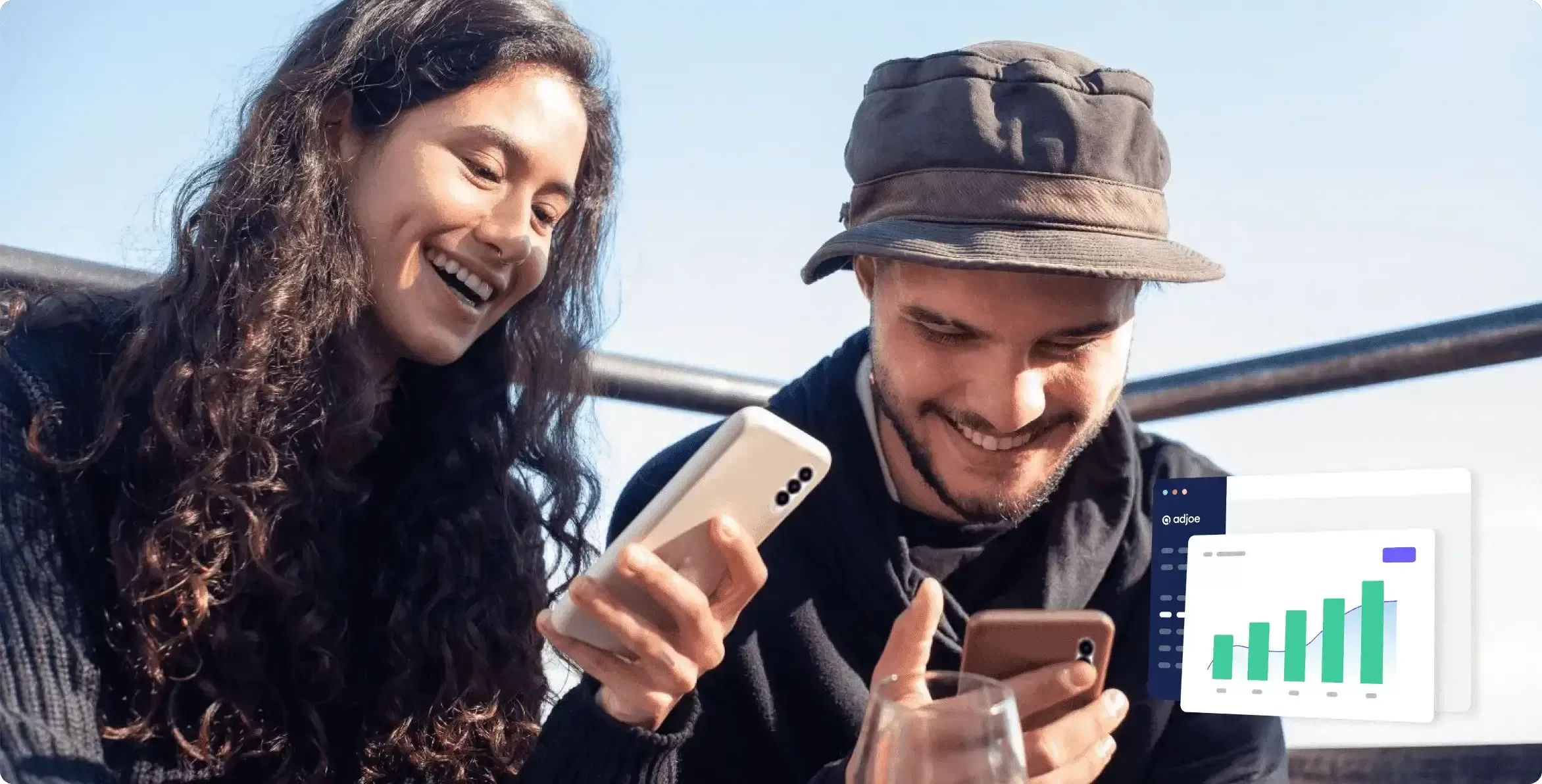 two young people outdoors laughing down at their phones