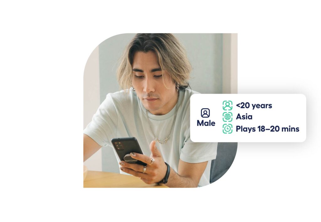 young man indoors holding his phone and looking down at it with decorative elements showing typical demographic for simulation games