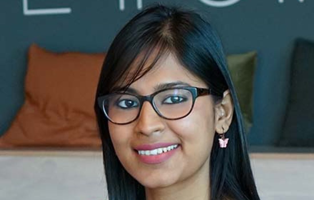 young woman with glasses smiling into the camera