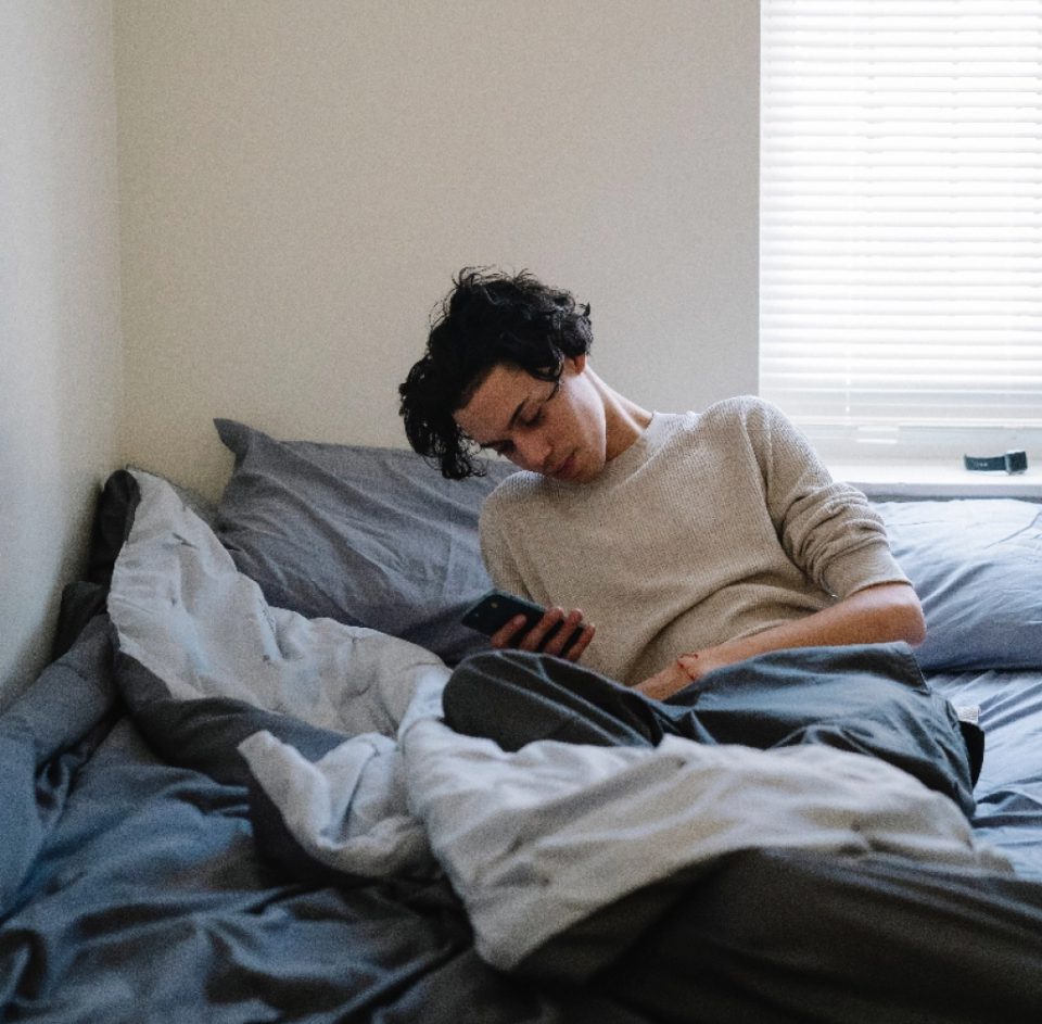 Young man in bed looking at his smartphone