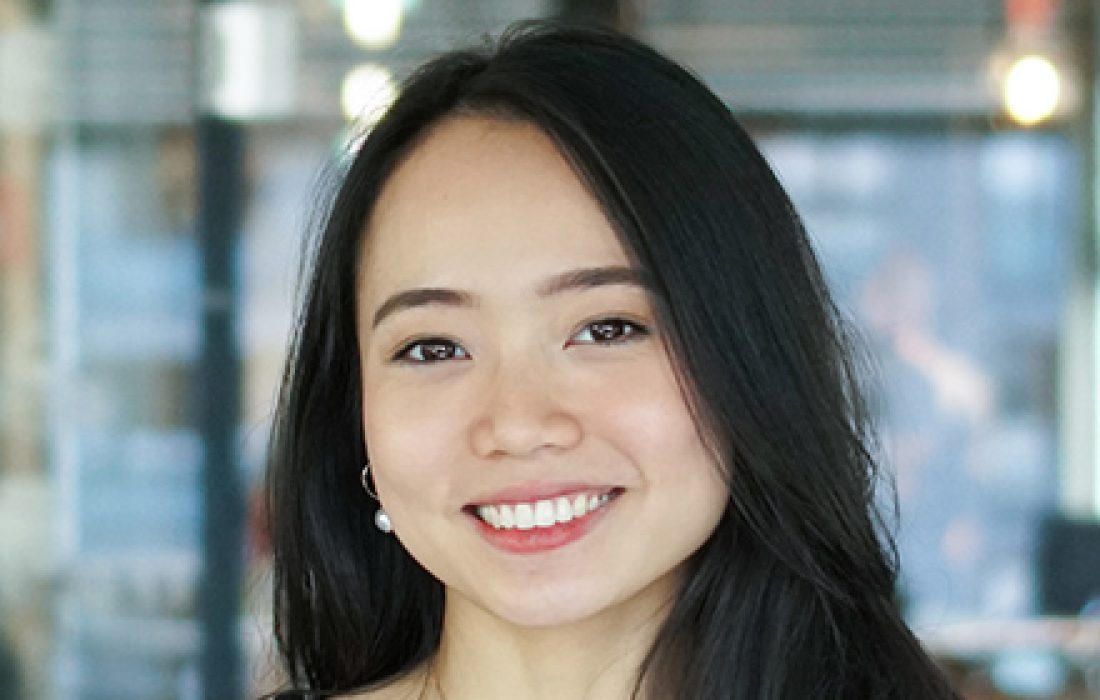 young woman with long dark hair and fair skin smiling into camera
