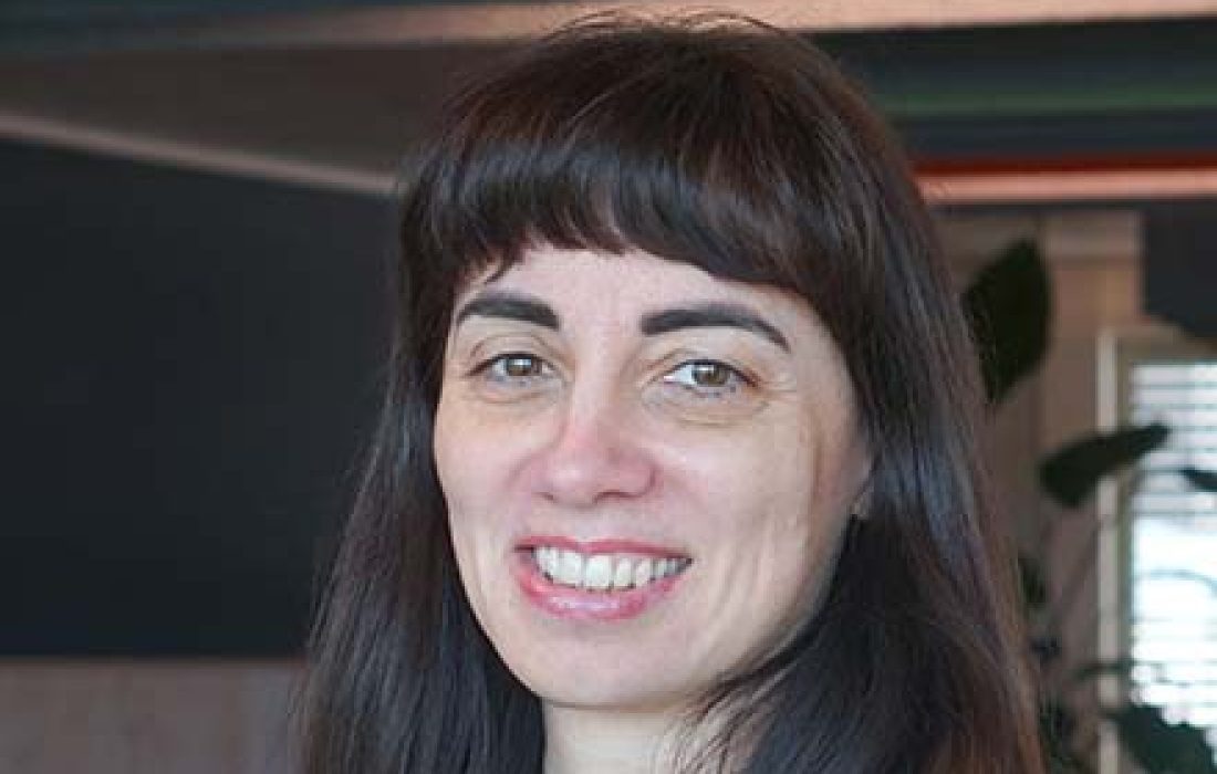 brunette woman with fringe smiling into the camera