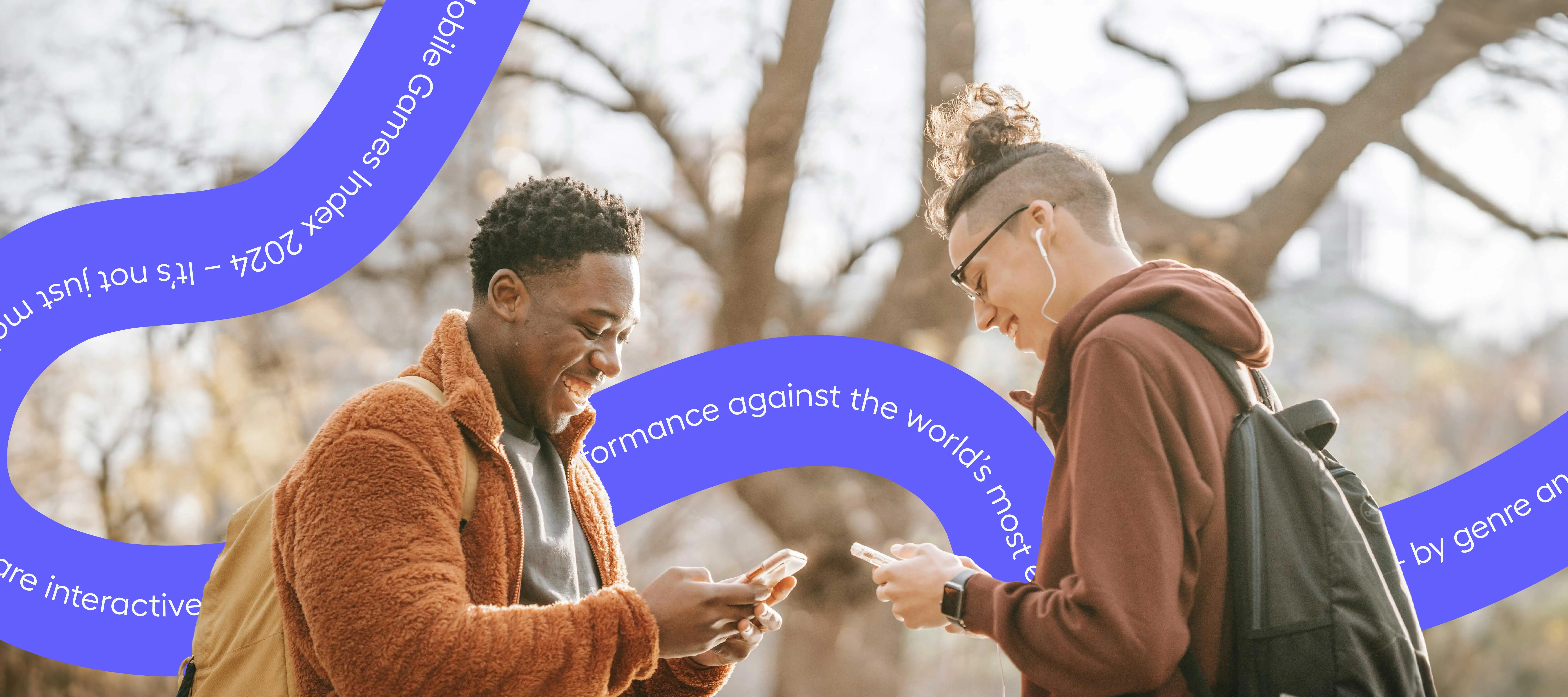 two young men outdoors smiling and looking down at their phones