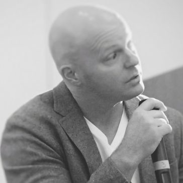 black and white image of man speaking into microphone