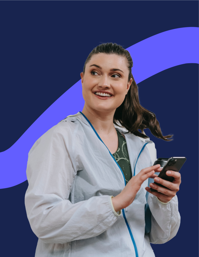woman with ponytail smiling and looking at her phone