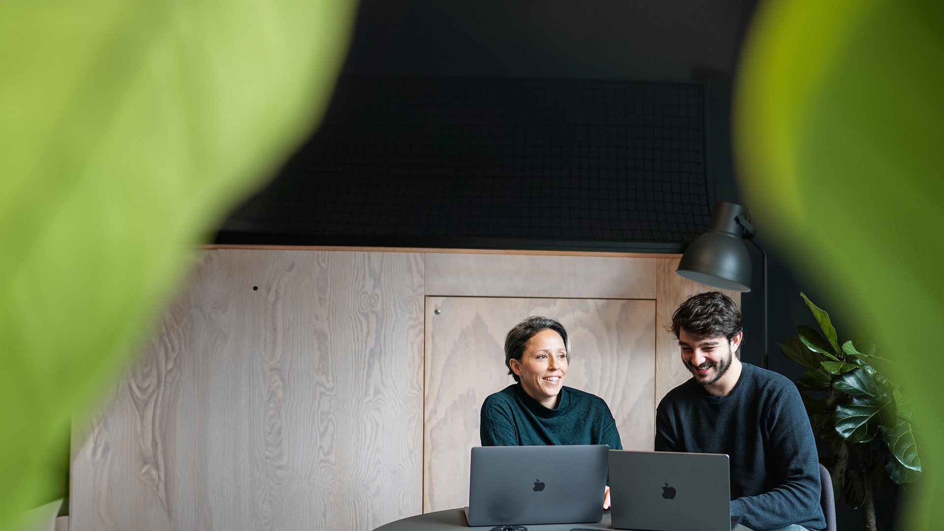 部屋の中でノートパソコンに向かって微笑んでいる2人の若者
