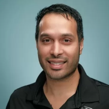 image of young man in black shirt smiling at camera